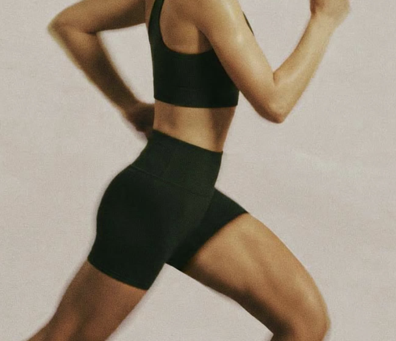 A runner mid-stride in soft sage tones